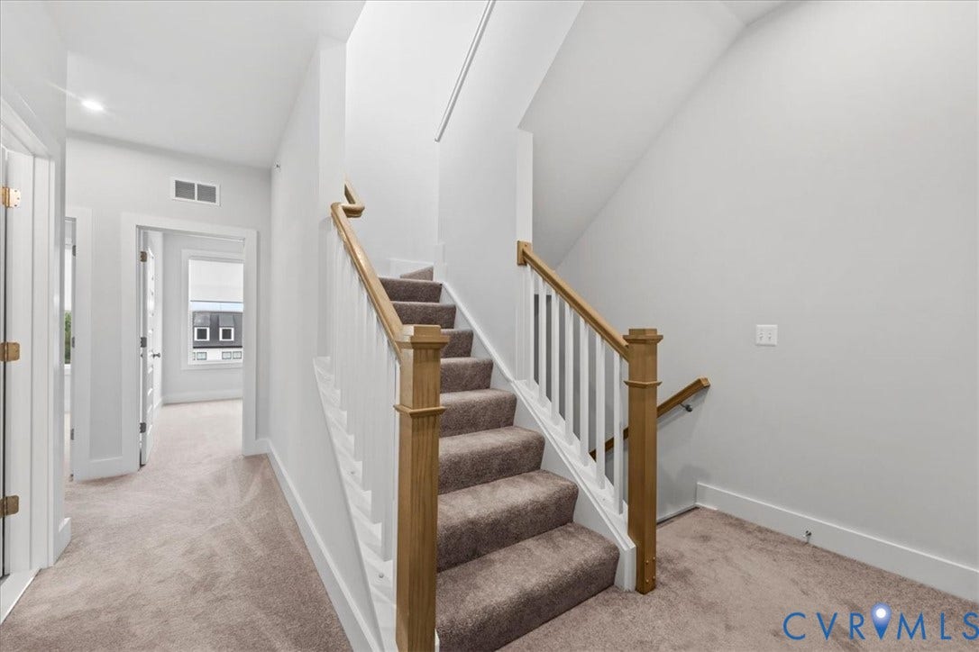 Carpeted staircase with wood handrails, white balusters, and recessed lighting