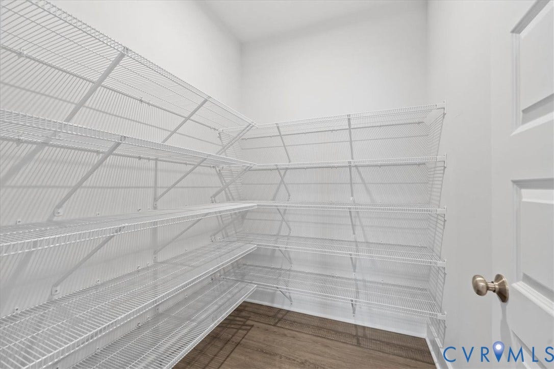 White wire shelving system, corner configuration, wood-finish flooring, white paneled door, brushed nickel doorknob