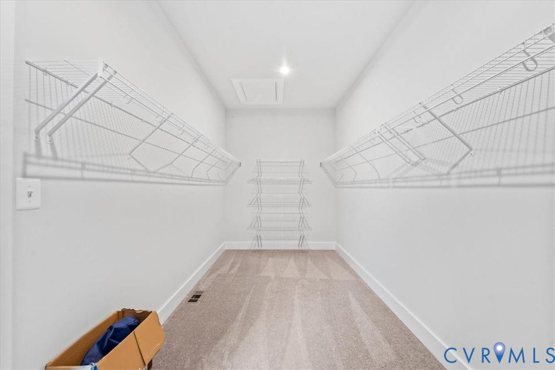 Carpeted flooring with white baseboards, recessed ceiling lighting, and wire shelving