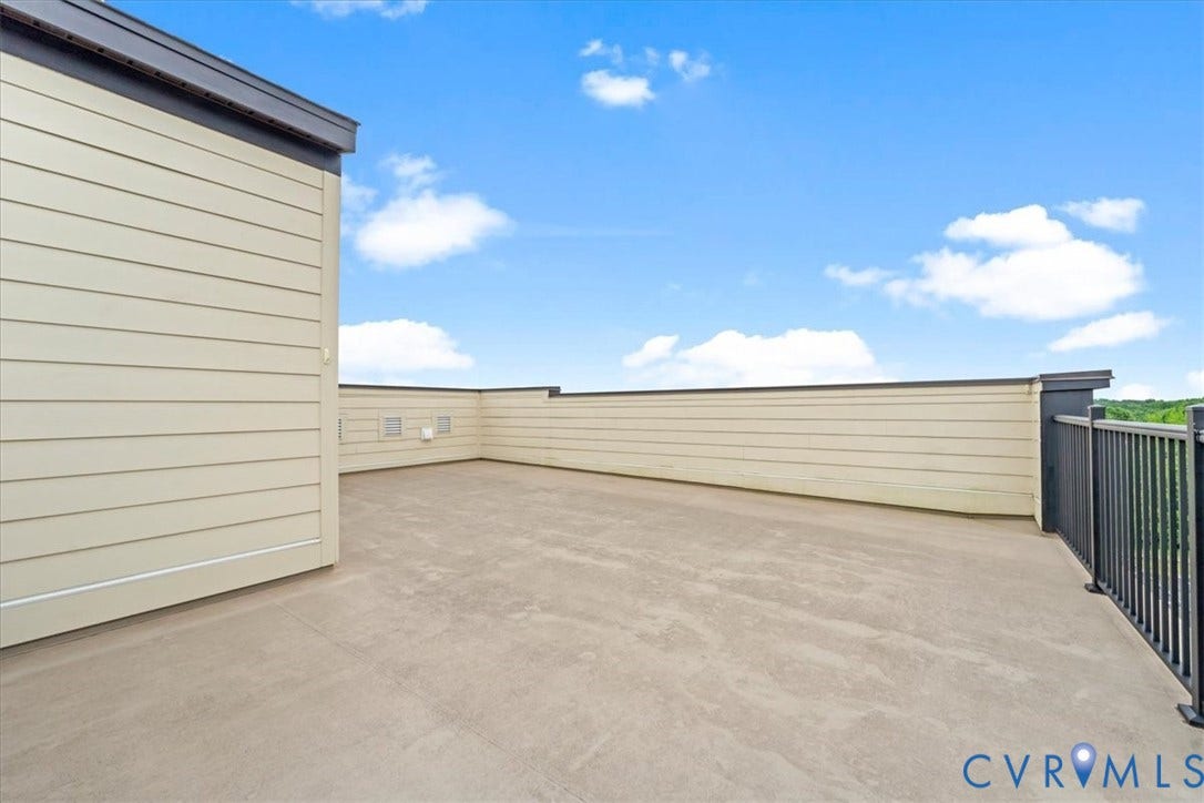 Expansive rooftop deck featuring a concrete surface, perimeter wall, and black metal railing