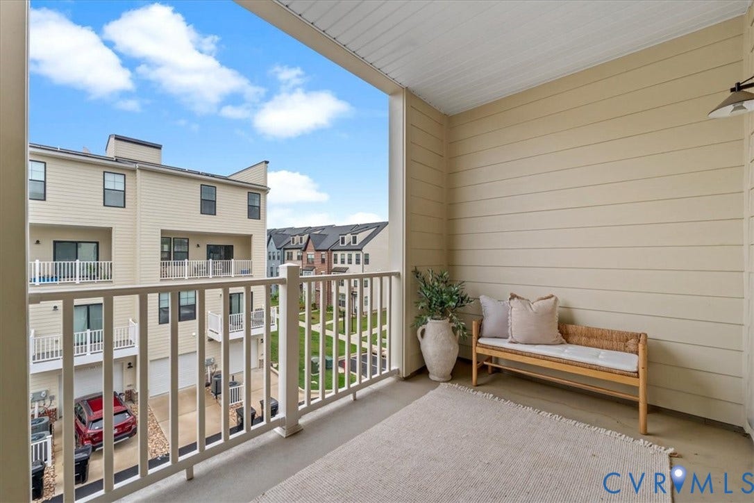Outdoor balcony with light-colored siding, a white railing, and an overhead outdoor light fixture