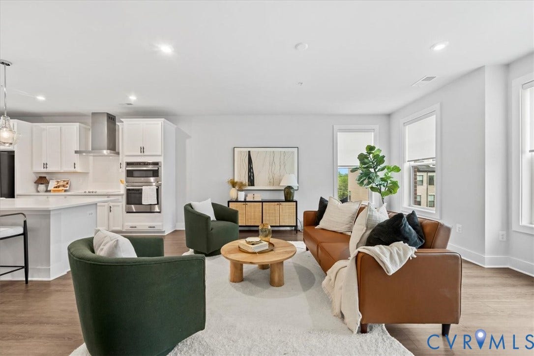 Open-concept living space with wood-finish flooring, white cabinetry, stainless steel appliances, a built-in double oven, and recessed lighting