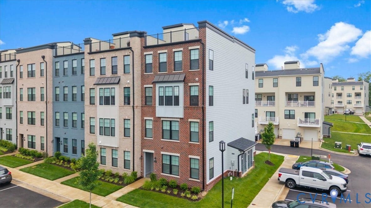 Modern townhome featuring a brick facade, bay window, and rooftop terrace