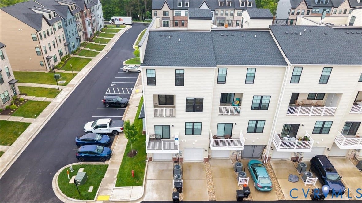 Multi-story townhome featuring private balconies, individual garages, and a paved driveway