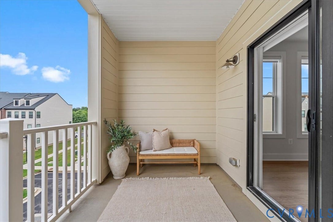 Outdoor balcony with a railing and siding, featuring a ceiling-mounted light fixture and sliding glass door