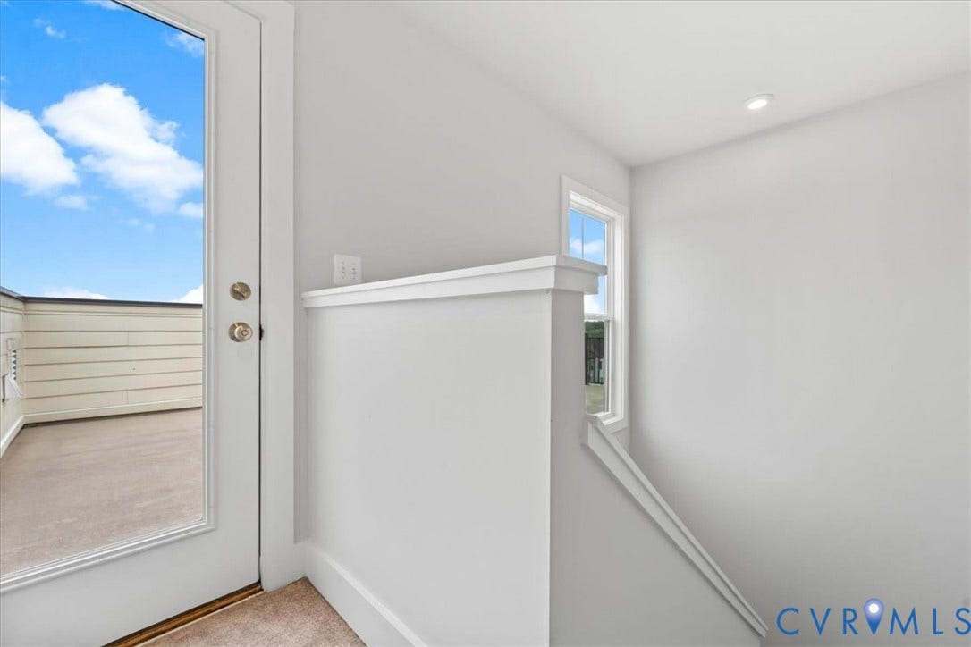 Glass-paneled door opening to an outdoor deck area, recessed ceiling lighting, and a single-pane window with white trim
