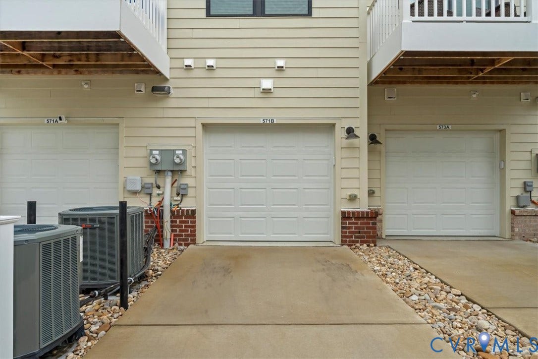 Individual garage entryways with panel doors, concrete driveway, and brick accents
