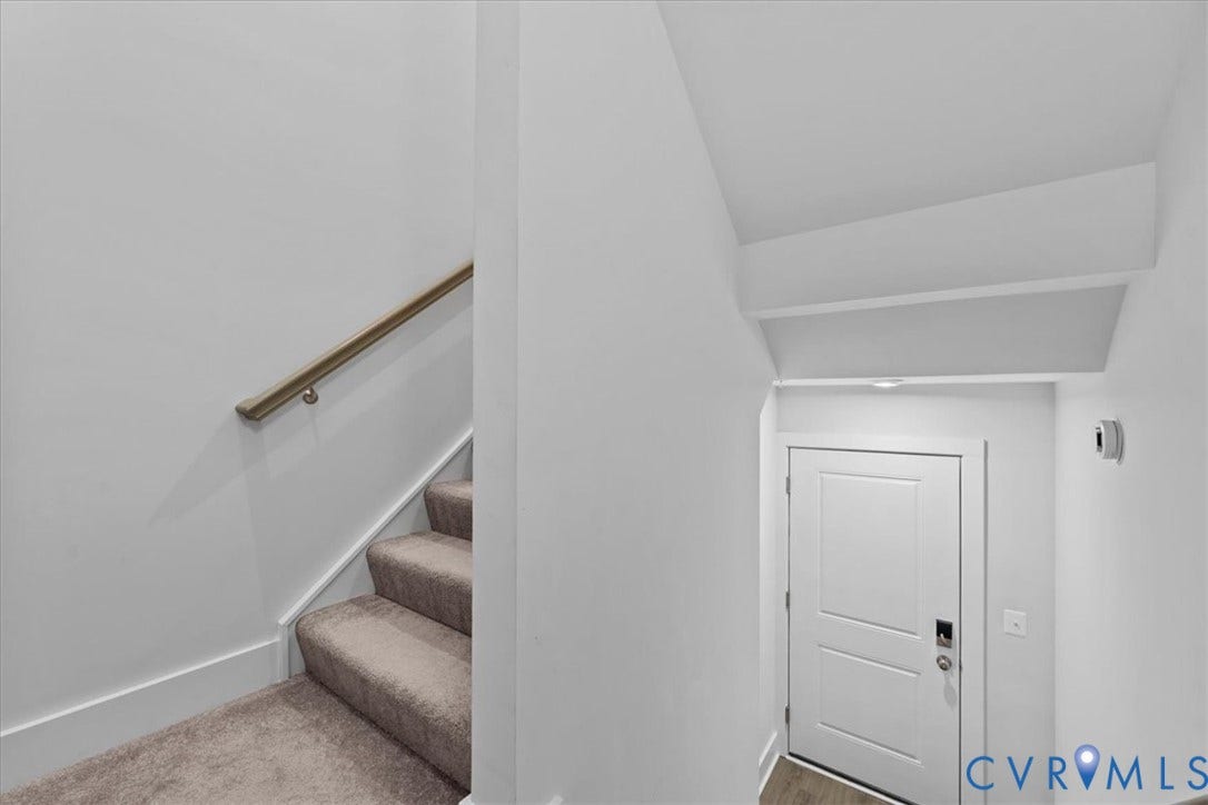 Carpeted stairs with a wood-finish handrail, white interior door with smart lock, and recessed lighting