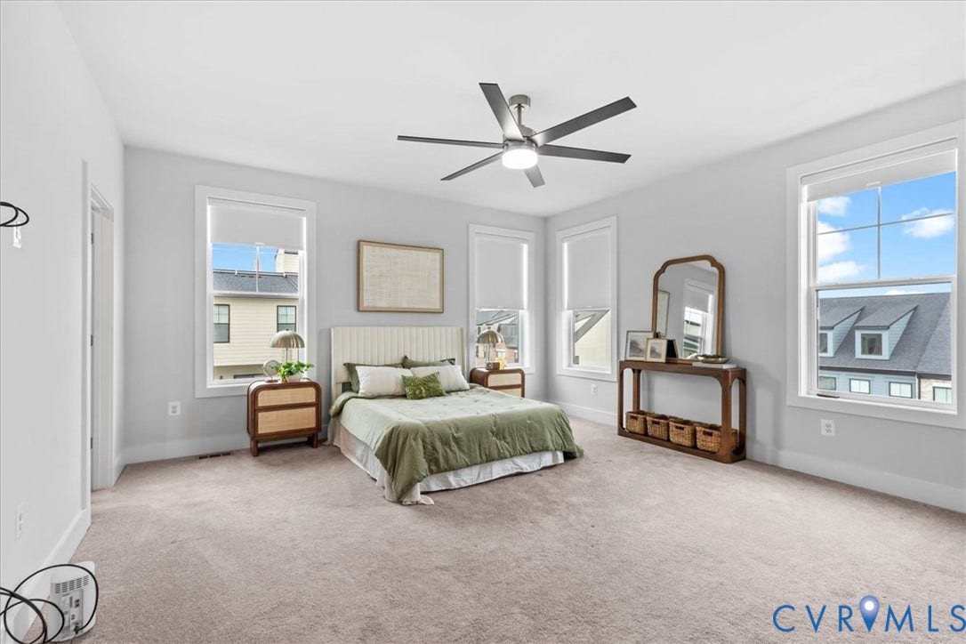 Spacious room with light-colored carpeting, multiple windows, and a ceiling fan