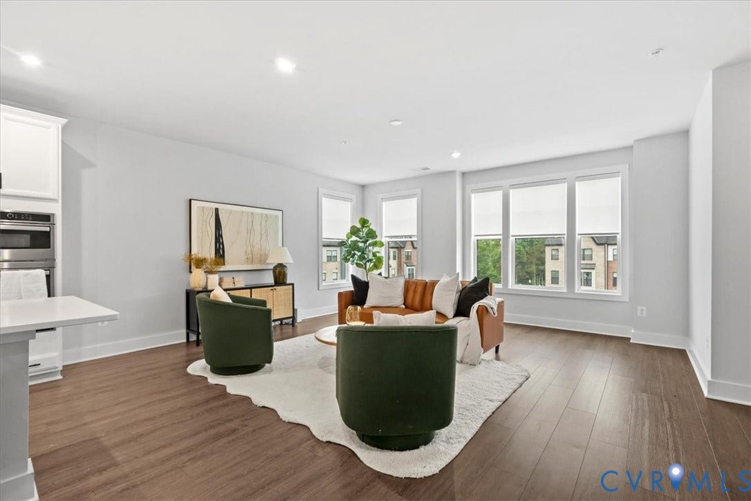 Open-concept living area with wood-finish flooring, recessed lighting, and multiple windows