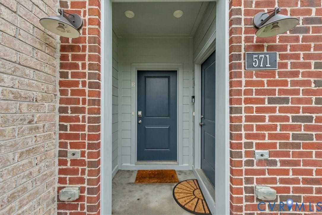 Brick exterior with two individual entrances, each featuring a panel door and overhead lighting