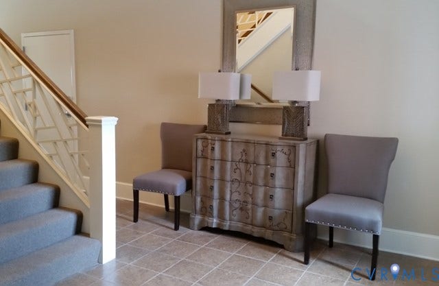 Staircase with wood railing and carpeted treads, complemented by tile flooring