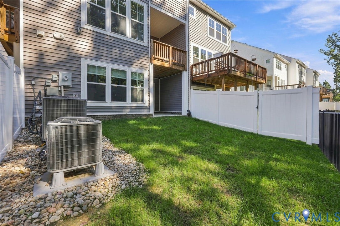 Expansive grassy area featuring a white privacy fence, multi-level wooden decks, and vinyl siding