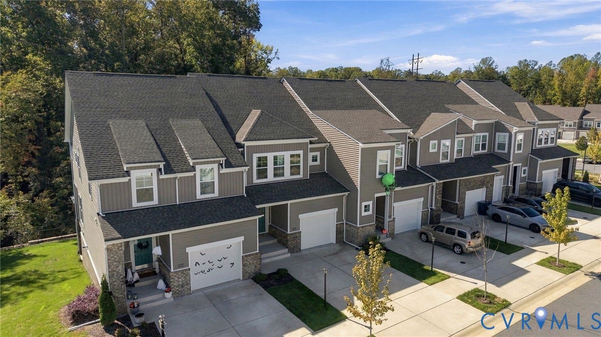 Townhome exterior featuring gray siding, stone accents, and dark shingle roofing