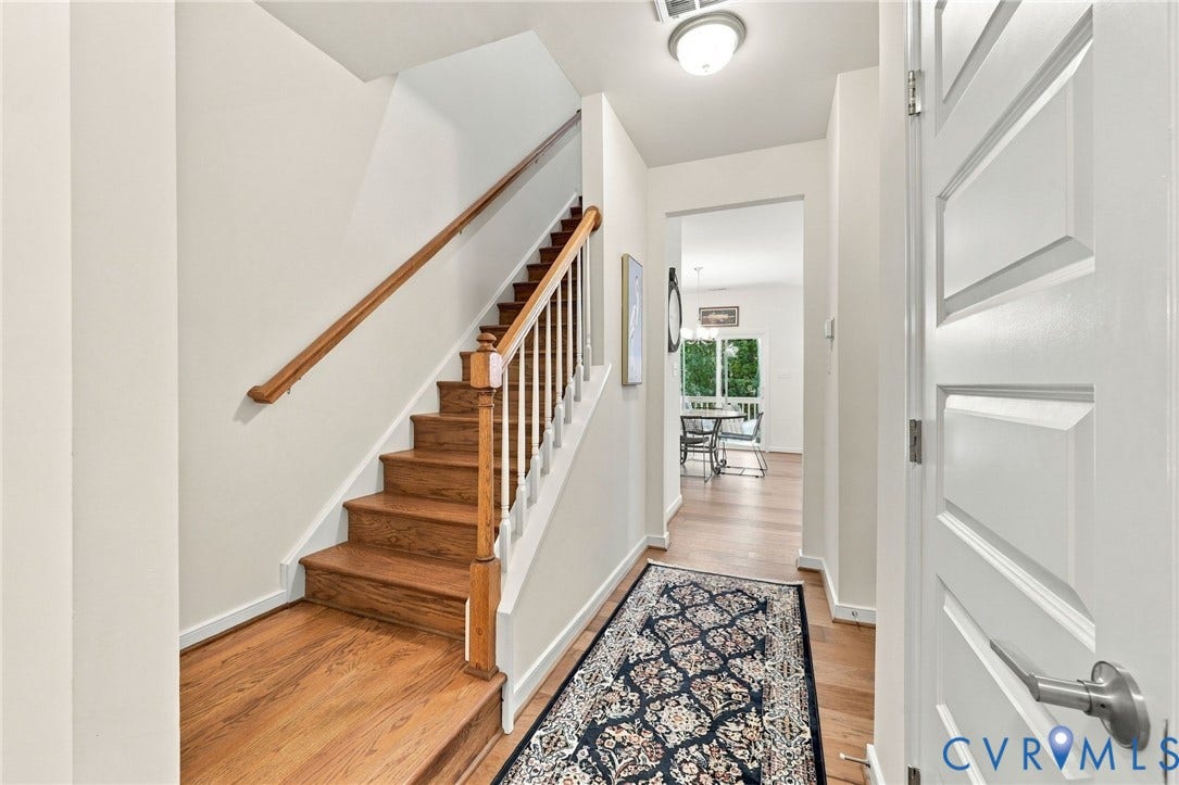Wood-finish flooring throughout, solid wood staircase with white risers, and a contemporary flush mount ceiling light