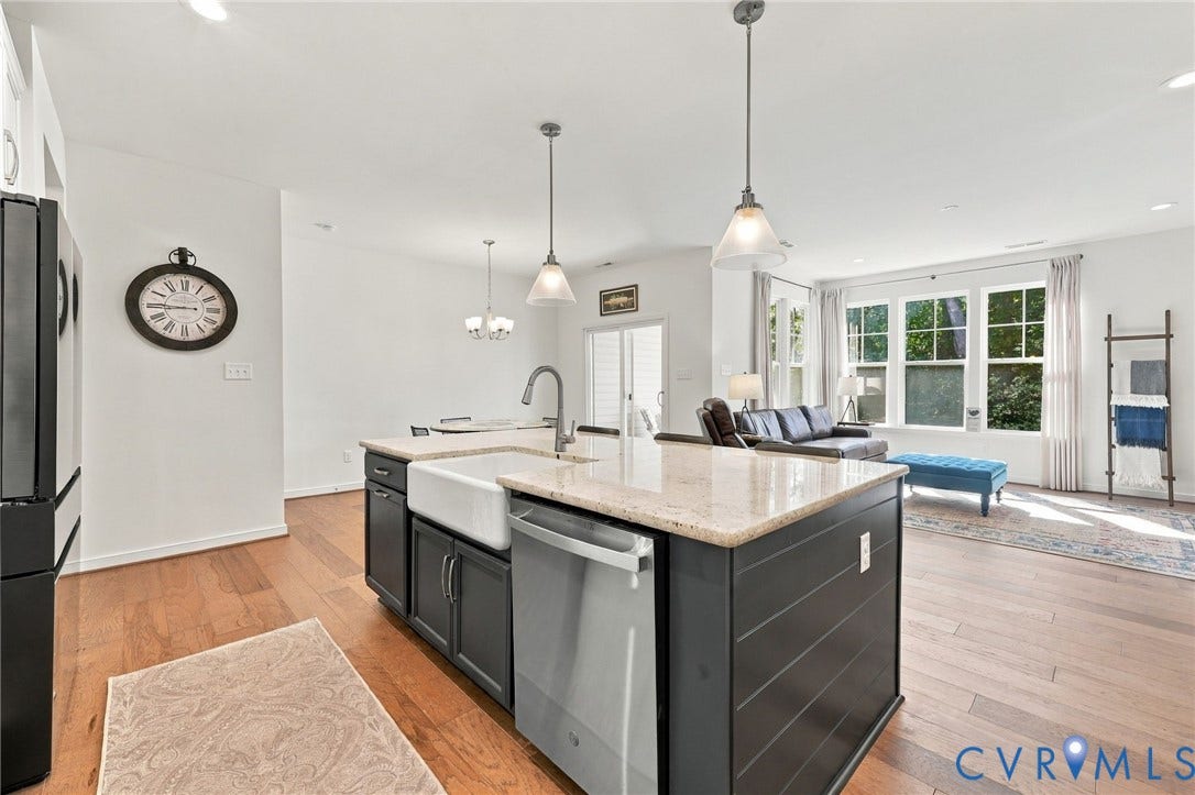 Kitchen island with a farmhouse sink, stainless steel dishwasher, and light-colored countertop