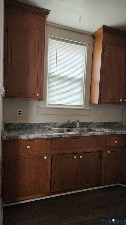 Wood-finish cabinetry with white knob hardware, laminate countertops, and a stainless steel double basin sink
