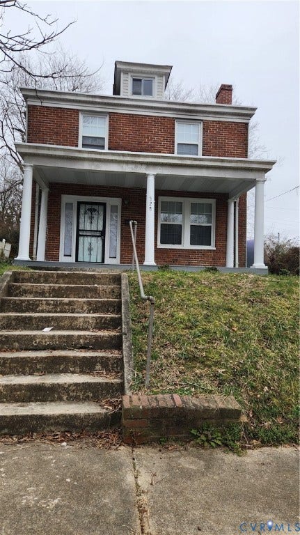 Brick exterior with white porch columns, a dormer window, and a prominent chimney