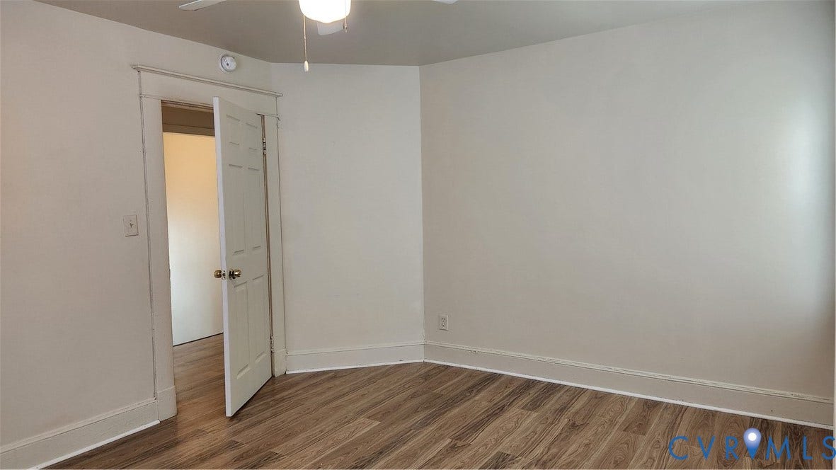 Wood-finish flooring, white painted walls, and a ceiling fan with integrated lighting