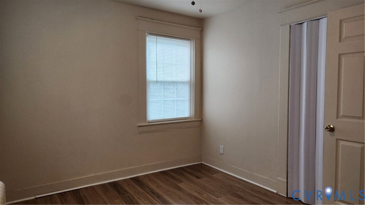 Wood-finish flooring, single window with blinds, and a bi-fold closet door