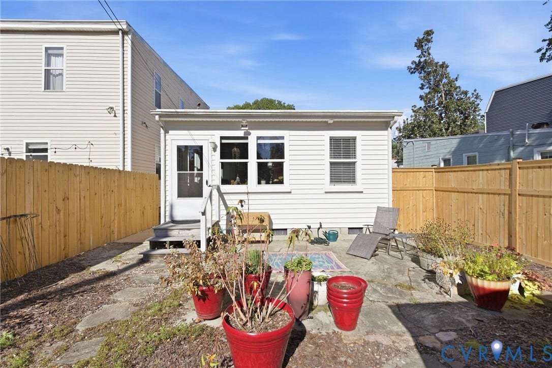 Rear exterior with white siding, multiple windows, and a wood privacy fence