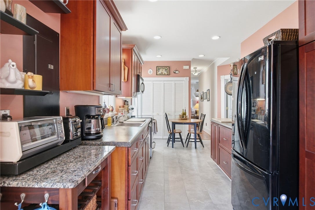 Galley kitchen featuring wood cabinetry, stone countertops, and tile flooring