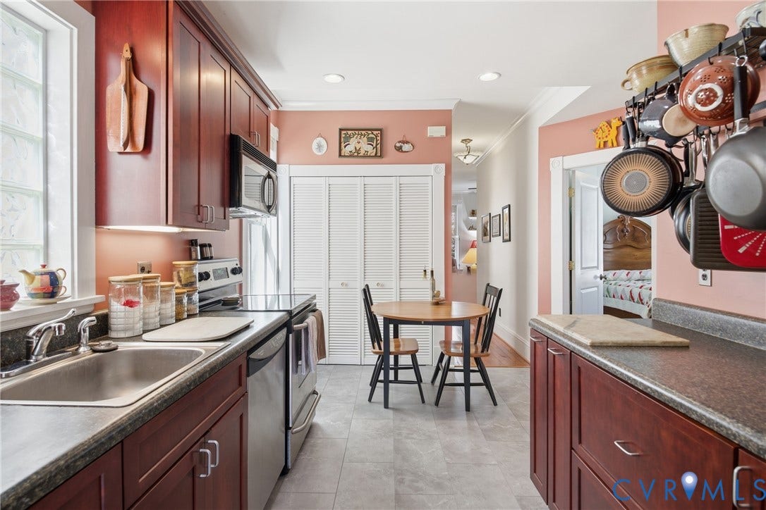 Galley kitchen featuring cherry wood-finish cabinetry, stainless steel appliances, and a built-in pot rack