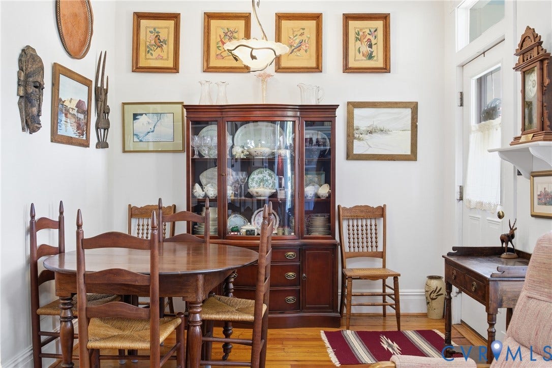 Hardwood flooring throughout, white painted walls, and a built-in display cabinet with glass doors