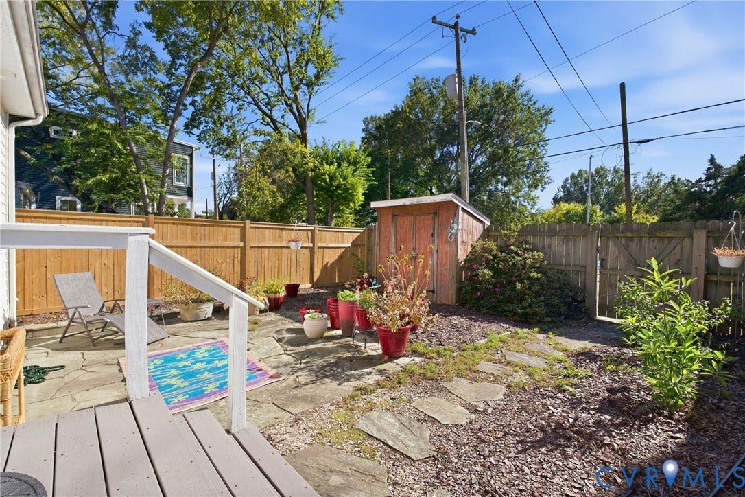 Private backyard featuring a wood privacy fence, flagstone patio, and a storage shed