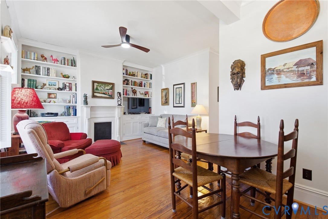 Hardwood flooring, built-in shelving, a ceiling fan, and a fireplace with a white mantel