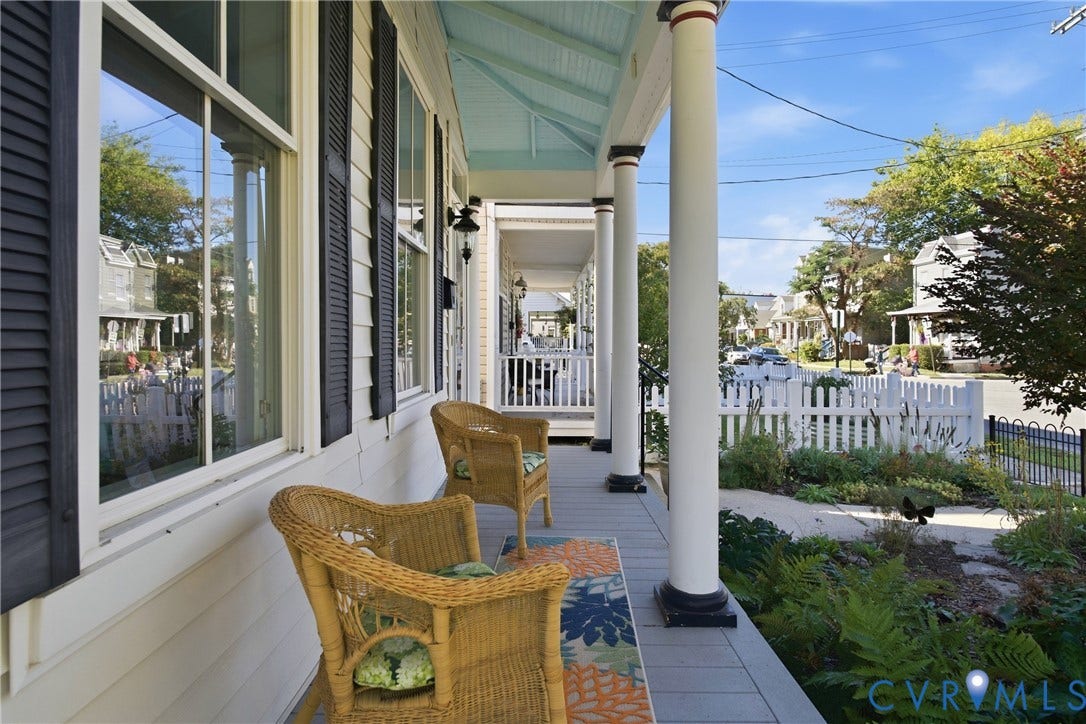 Expansive covered porch featuring substantial white columns, a light blue ceiling, and white siding