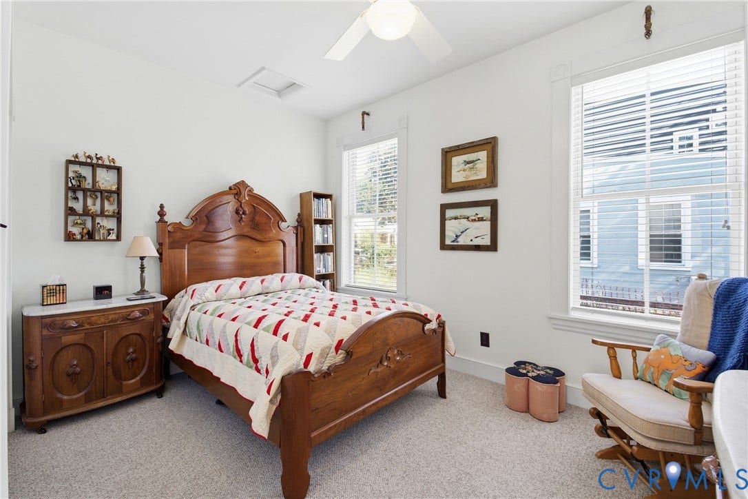 Recessed ceiling light, ceiling fan, two windows with blinds, built-in shelving, light-toned carpeting