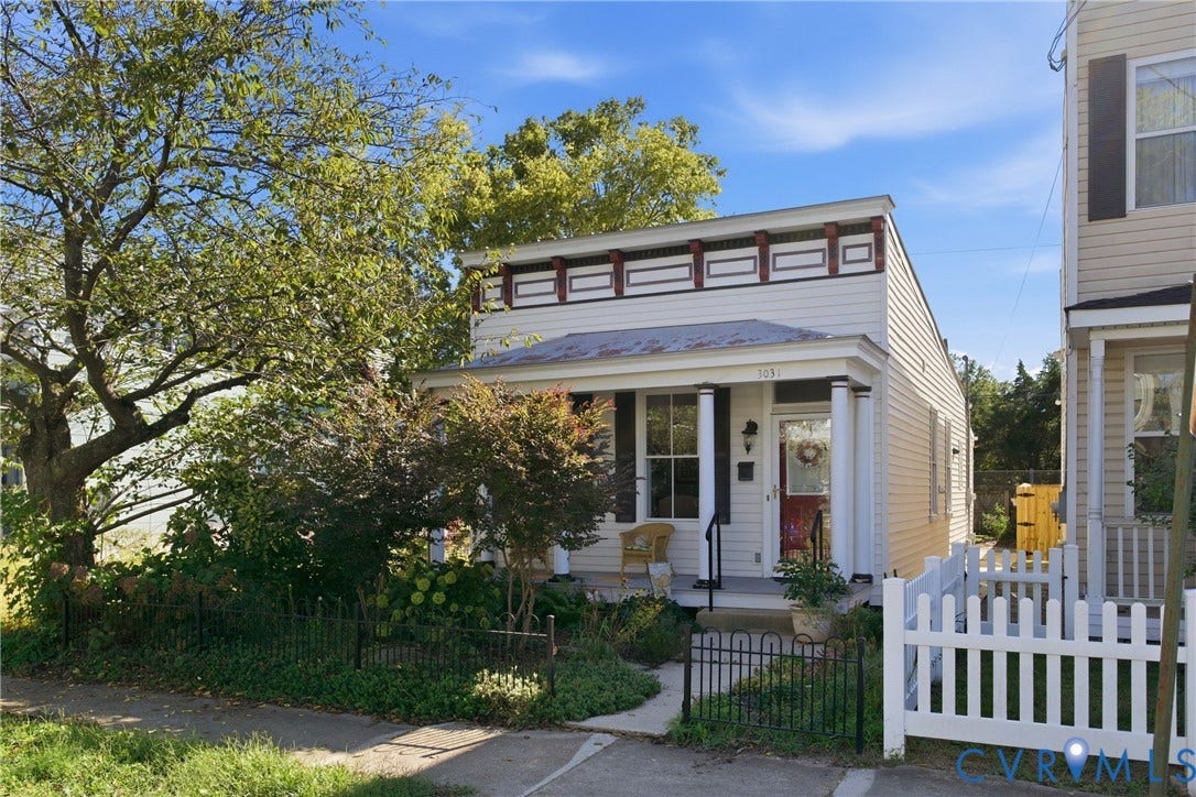Siding exterior with decorative frieze, covered porch with columns, and white picket fencing