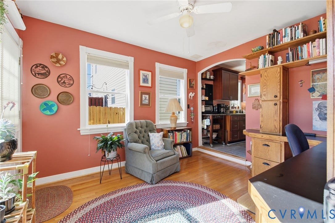 Hardwood flooring throughout, arched doorway, built-in shelving, multiple windows with white trim, and a ceiling fan