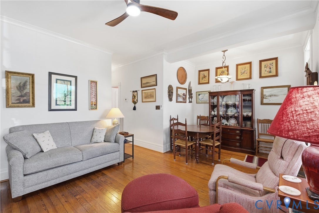 Hardwood flooring, crown molding, ceiling fan, recessed ceiling detail, and a built-in display cabinet