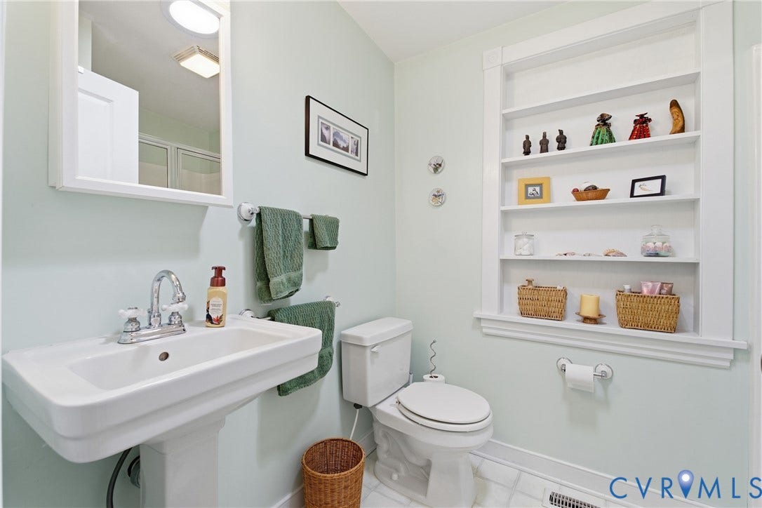 Pedestal sink with chrome faucet, built-in shelving, white tiled flooring, and a white toilet