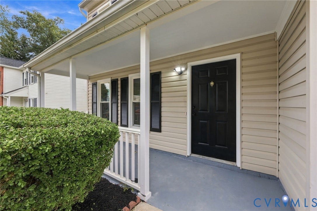 5831 Larrymore Road, Richmond, VA 23225 Covered front porch featuring white railings, neutral siding, dark exterior shutters, and a paneled entry door with hardware