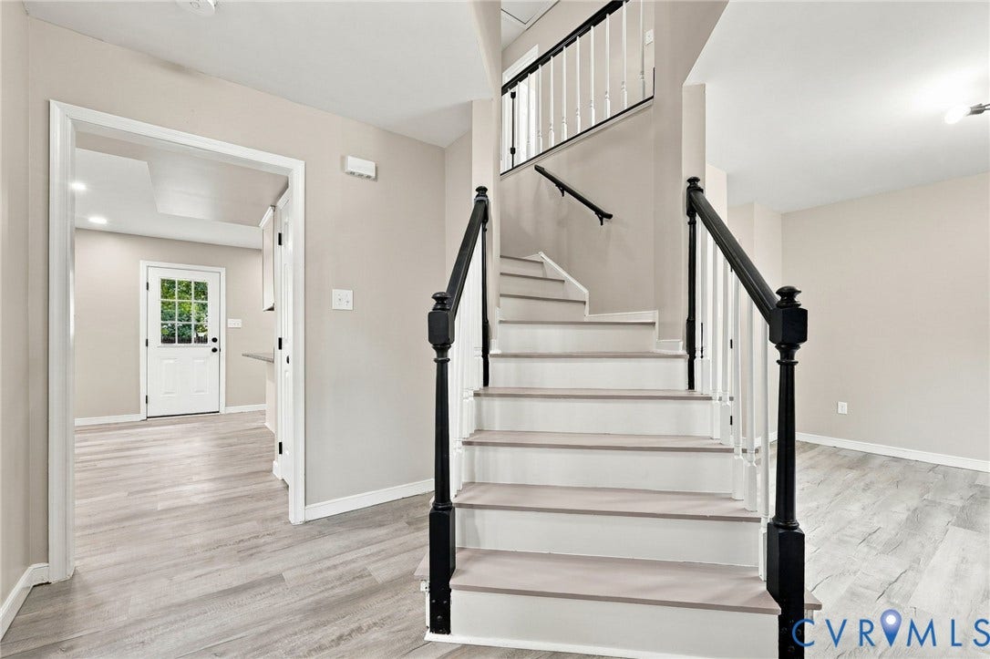 5831 Larrymore Road, Richmond, VA 23225 Staircase featuring wood-finish treads, white risers, and a balustrade with black newel posts and handrails