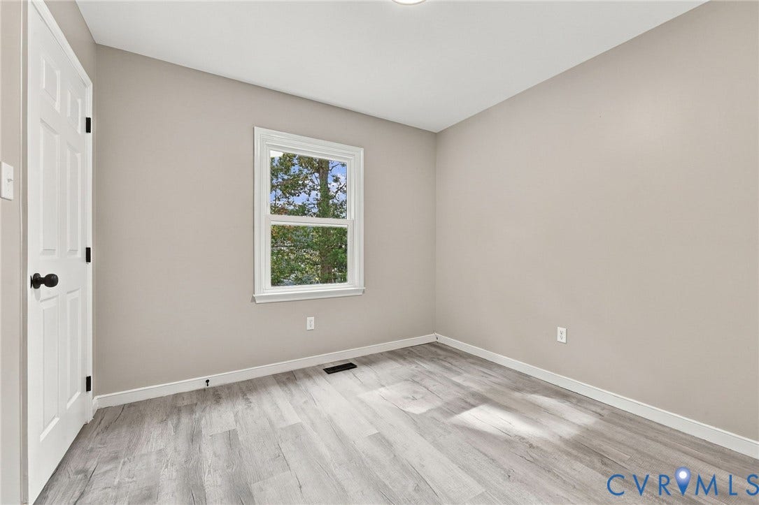 5831 Larrymore Road, Richmond, VA 23225 Neutral-toned interior space featuring wood-finish flooring, a six-panel door with dark hardware, and a single window