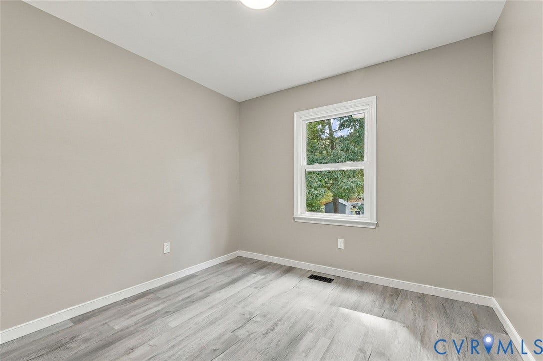 5831 Larrymore Road, Richmond, VA 23225 Neutral-toned interior space featuring light wood-finish flooring, a double-hung window with white casing, and a flush-mount ceiling light