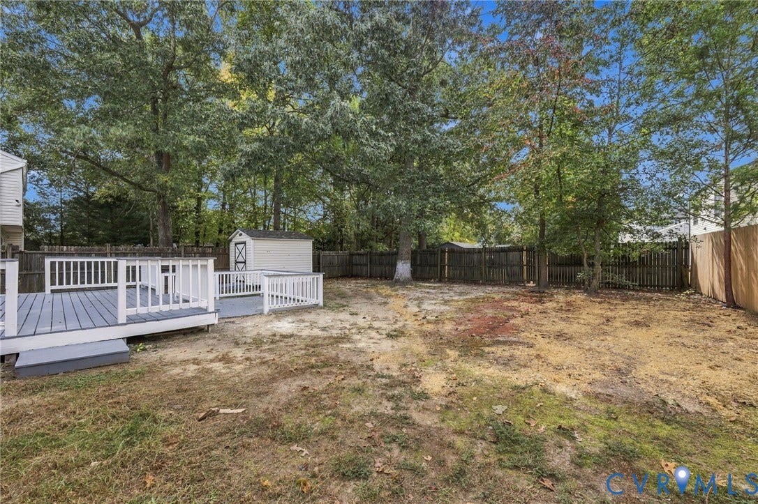 5831 Larrymore Road, Richmond, VA 23225 Multi-level wooden deck featuring white balustrades, detached storage shed, and perimeter wood privacy fencing