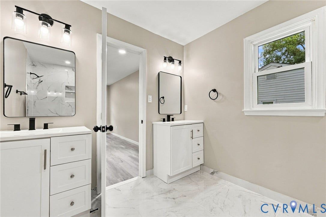 5831 Larrymore Road, Richmond, VA 23225 Dual white vanities featuring integrated sinks, polished stone-finish countertops, matte black fixtures, and matching framed mirrors, complemented by large-format porcelain tile flooring and multi-bulb wall-mounted lighting
