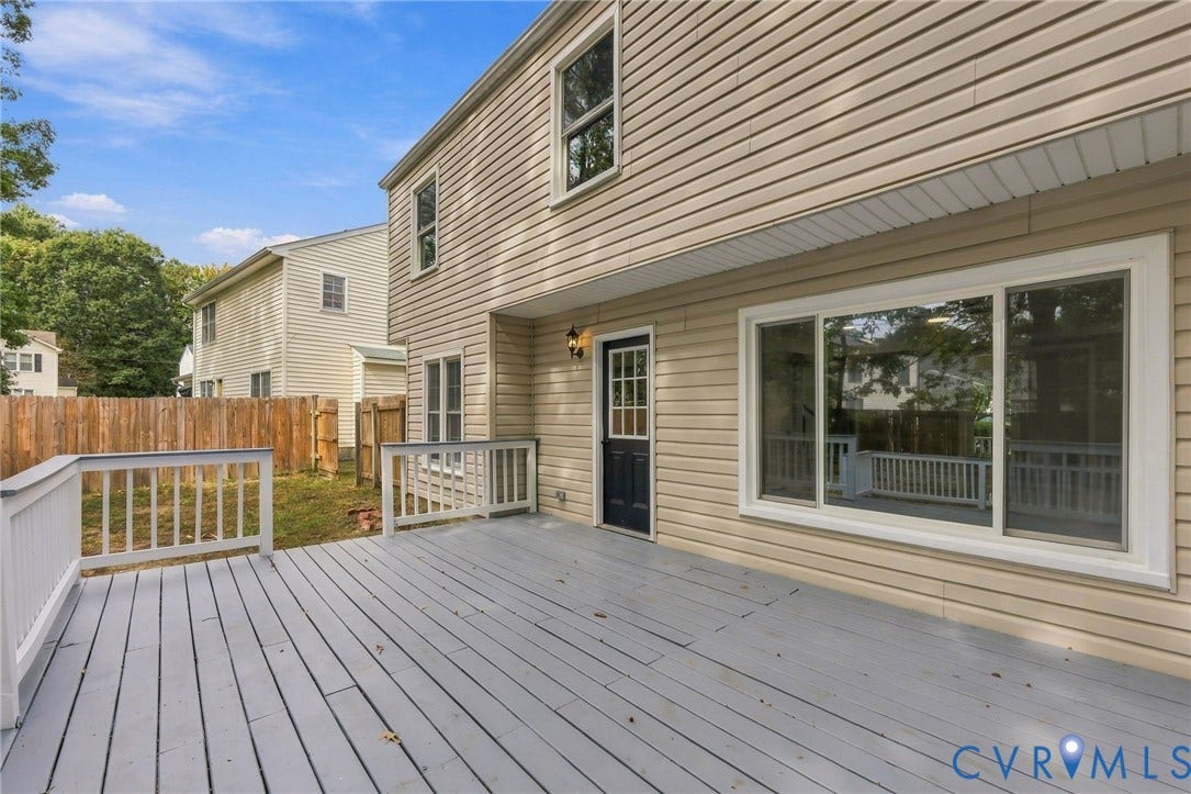 5831 Larrymore Road, Richmond, VA 23225 Rear exterior featuring light-toned horizontal siding, a gray-painted wood deck with matching balustrades, a large sliding glass door, and a single-light exterior entry door