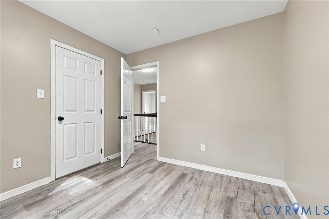 5831 Larrymore Road, Richmond, VA 23225 Room featuring neutral wall paint, wood-finish flooring, and a six-panel interior door with matte black hardware