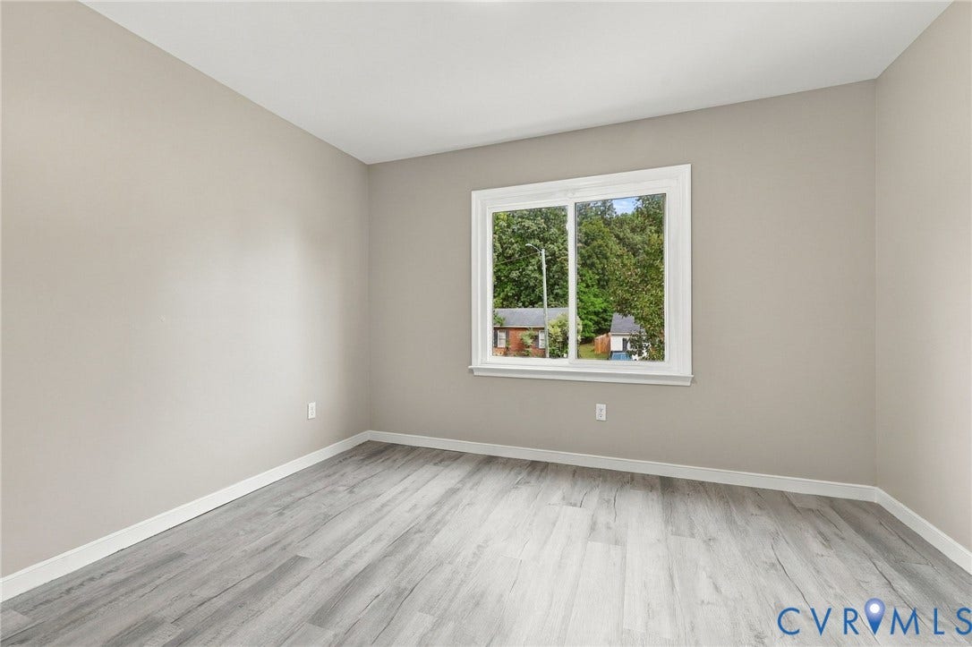 5831 Larrymore Road, Richmond, VA 23225 Neutral interior room featuring wood-finish flooring, light gray wall paint, and a sliding window