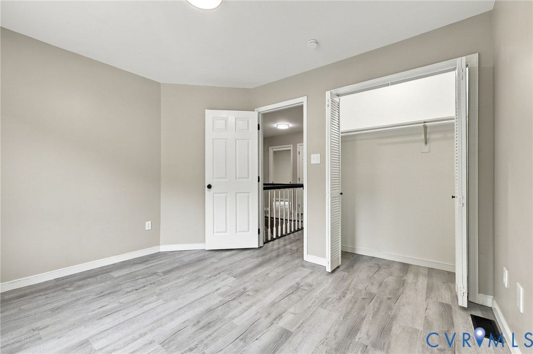 5831 Larrymore Road, Richmond, VA 23225 Neutral-toned interior room featuring wood-finish flooring, six-panel interior door, and a reach-in closet with bi-fold louvered doors