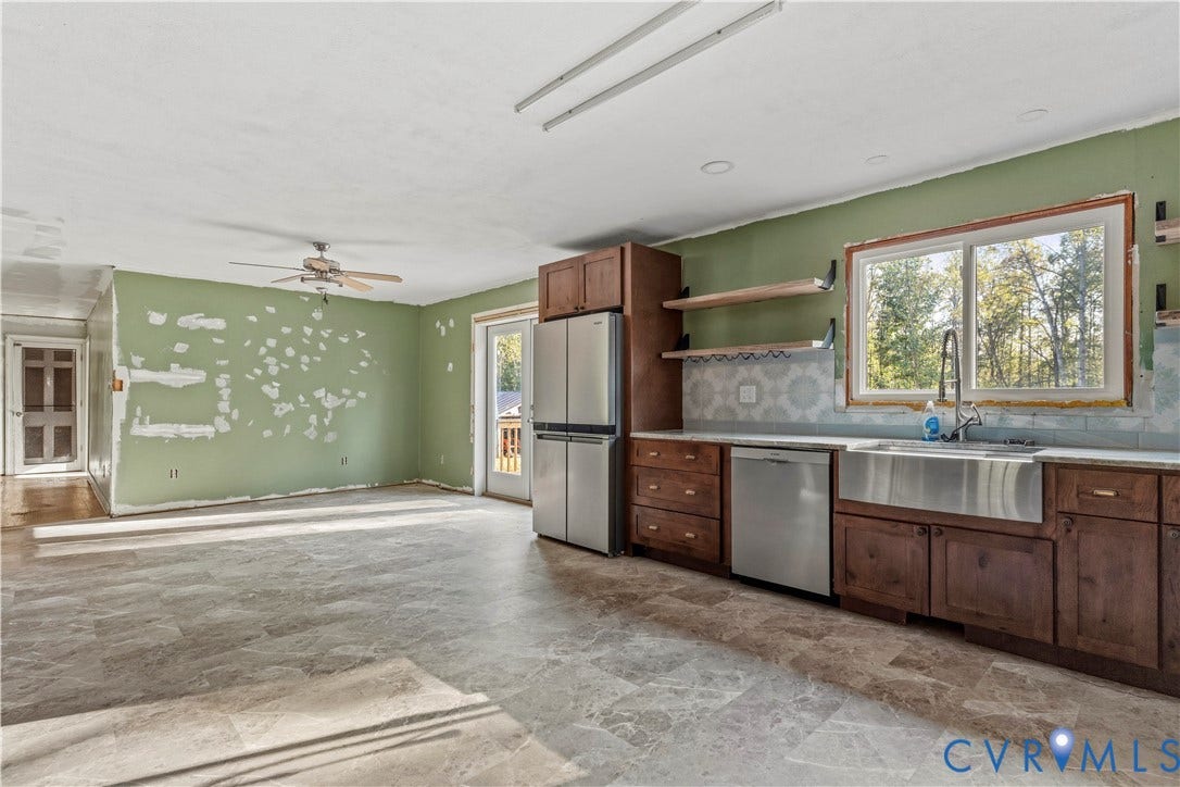 Stainless steel appliances, wood-finish cabinetry, farmhouse sink, decorative tile backsplash, and open shelving