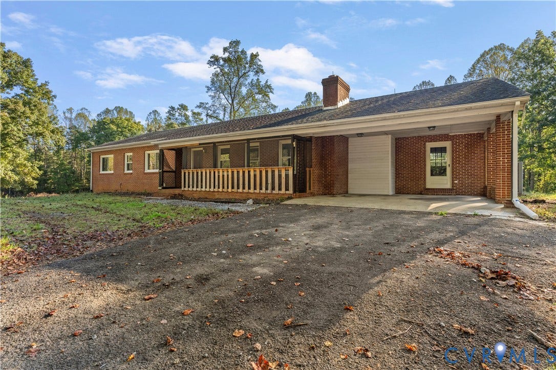 Brick exterior residence featuring a covered carport, screened porch with wood railings, and a prominent brick chimney