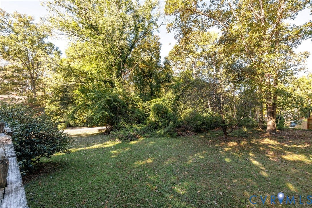 Expansive backyard featuring a lush grass lawn, mature trees, and a wooden perimeter fence