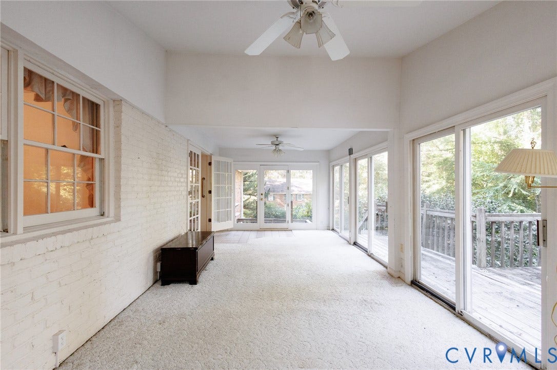 Sunroom featuring white painted brick walls, multi-panel sliding glass doors, double glass-pane doors, and dual ceiling fans